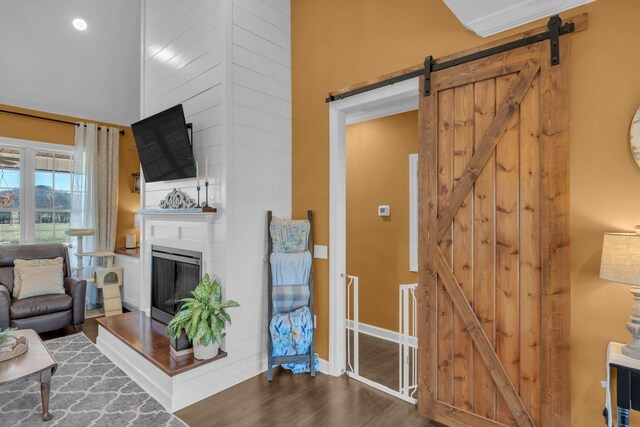 living room with a fireplace, a barn door, and dark wood-type flooring