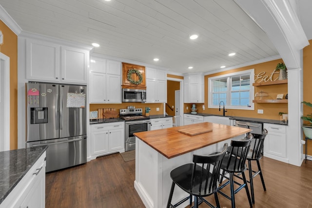 kitchen featuring white cabinetry, a kitchen bar, appliances with stainless steel finishes, dark hardwood / wood-style floors, and ornamental molding