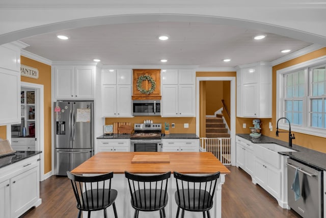 kitchen with stainless steel appliances, crown molding, and white cabinets