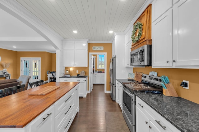 kitchen with dark hardwood / wood-style floors, stainless steel appliances, crown molding, and white cabinets