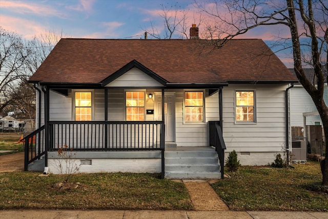 bungalow-style house featuring covered porch and a lawn