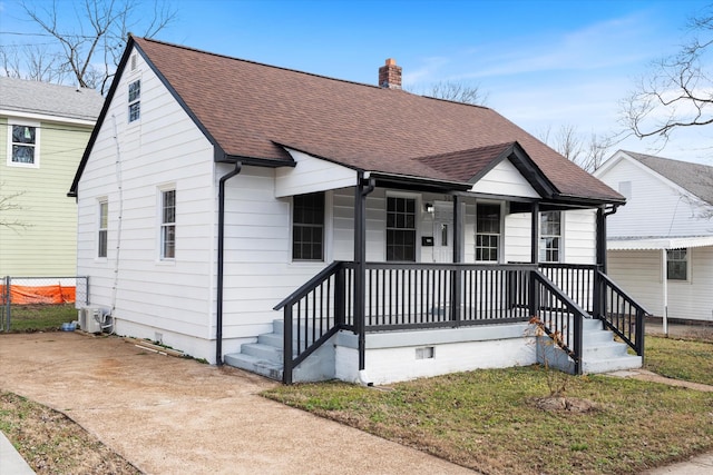 bungalow featuring covered porch and a front yard