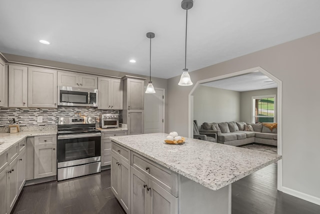 kitchen featuring tasteful backsplash, dark hardwood / wood-style floors, a center island, pendant lighting, and appliances with stainless steel finishes