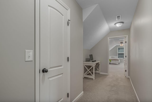 hall featuring light carpet and vaulted ceiling