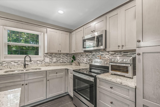 kitchen featuring light stone countertops, sink, gray cabinetry, and stainless steel appliances