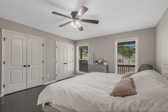 bedroom with ceiling fan, dark wood-type flooring, and two closets