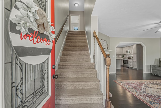 stairs featuring ceiling fan and hardwood / wood-style floors