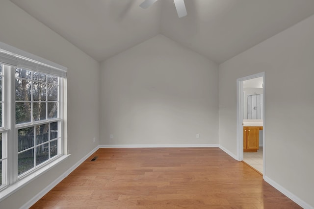 spare room featuring lofted ceiling, light wood-type flooring, plenty of natural light, and ceiling fan