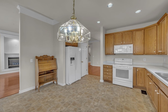 kitchen featuring a notable chandelier, sink, hanging light fixtures, and white appliances