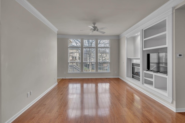 unfurnished living room featuring ceiling fan, built in features, ornamental molding, and light hardwood / wood-style flooring