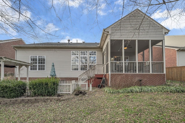 rear view of house with ceiling fan, a sunroom, and a lawn