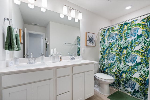 bathroom with toilet, vanity, and tile patterned floors