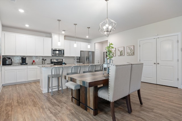 dining area with light hardwood / wood-style flooring and a notable chandelier