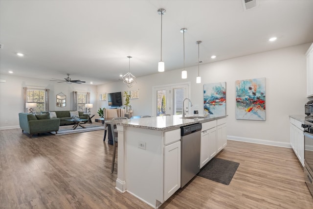 kitchen featuring ceiling fan with notable chandelier, appliances with stainless steel finishes, white cabinetry, an island with sink, and hanging light fixtures