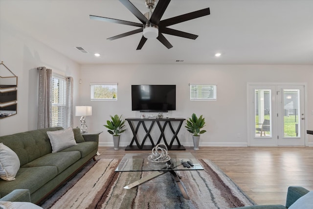 living room with light wood-type flooring, ceiling fan, and plenty of natural light