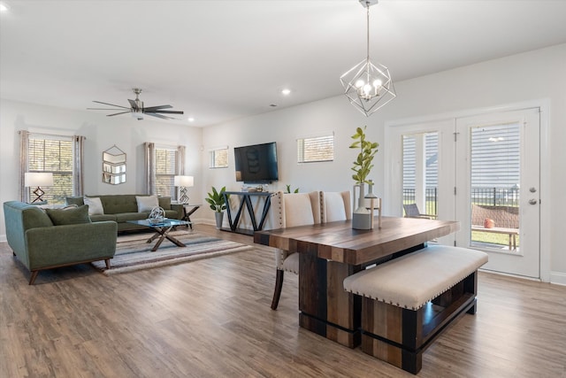 dining space with ceiling fan with notable chandelier and hardwood / wood-style floors