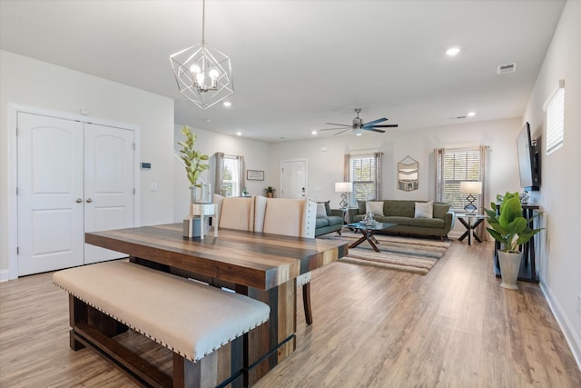 dining space with light wood-type flooring and ceiling fan with notable chandelier