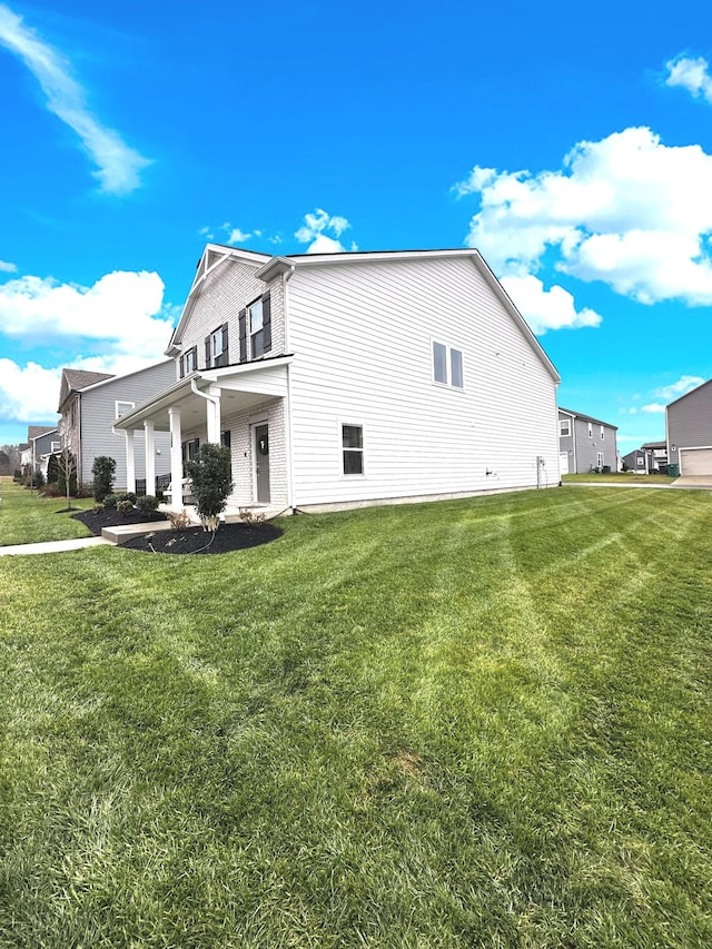 view of side of property with covered porch and a yard