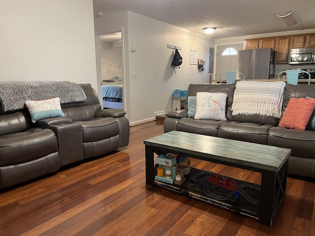 living room with a textured ceiling and dark wood-type flooring