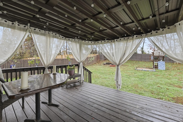 wooden terrace with a playground and a lawn