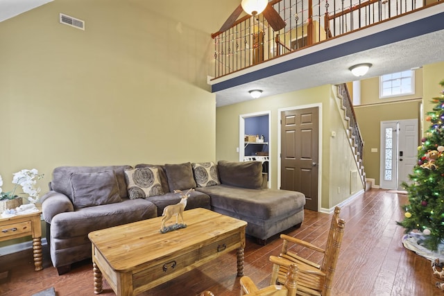 living room featuring ceiling fan, a towering ceiling, and hardwood / wood-style floors