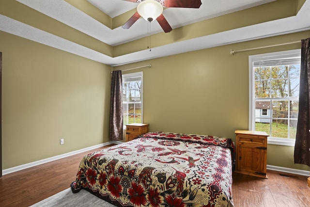 bedroom featuring ceiling fan, hardwood / wood-style flooring, and a tray ceiling