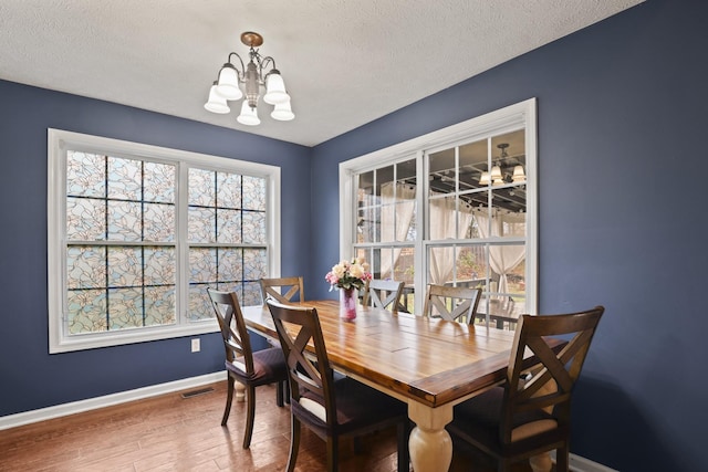 dining room with a textured ceiling, a chandelier, and wood-type flooring