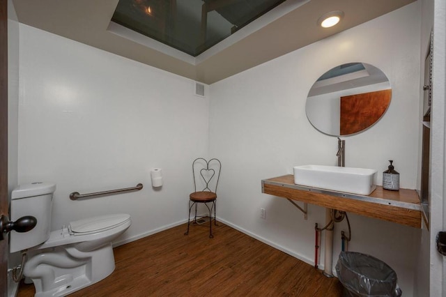 bathroom with toilet, wood-type flooring, and sink