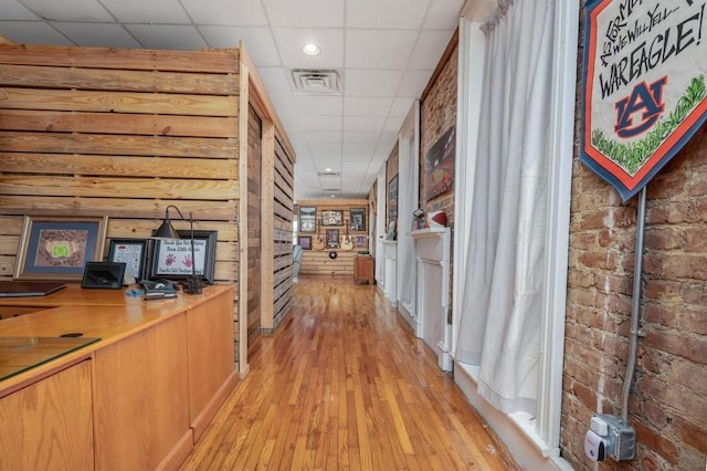 hallway featuring light wood-type flooring and a drop ceiling