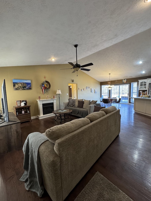 living room featuring a textured ceiling, vaulted ceiling, ceiling fan with notable chandelier, and dark hardwood / wood-style floors