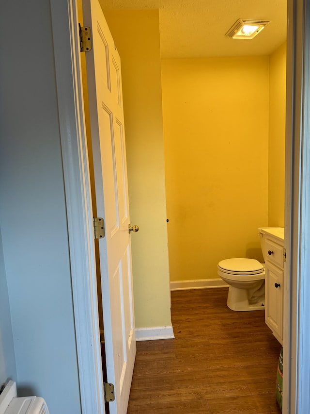 bathroom featuring toilet, wood-type flooring, and vanity