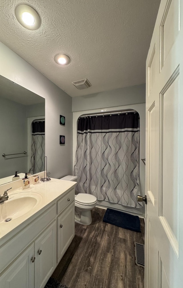 bathroom featuring toilet, vanity, a textured ceiling, and hardwood / wood-style floors