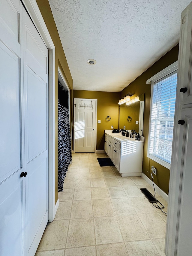 bathroom with a textured ceiling, tile patterned floors, and vanity