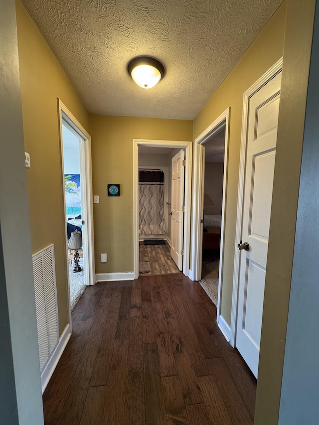 corridor with a textured ceiling and dark hardwood / wood-style floors