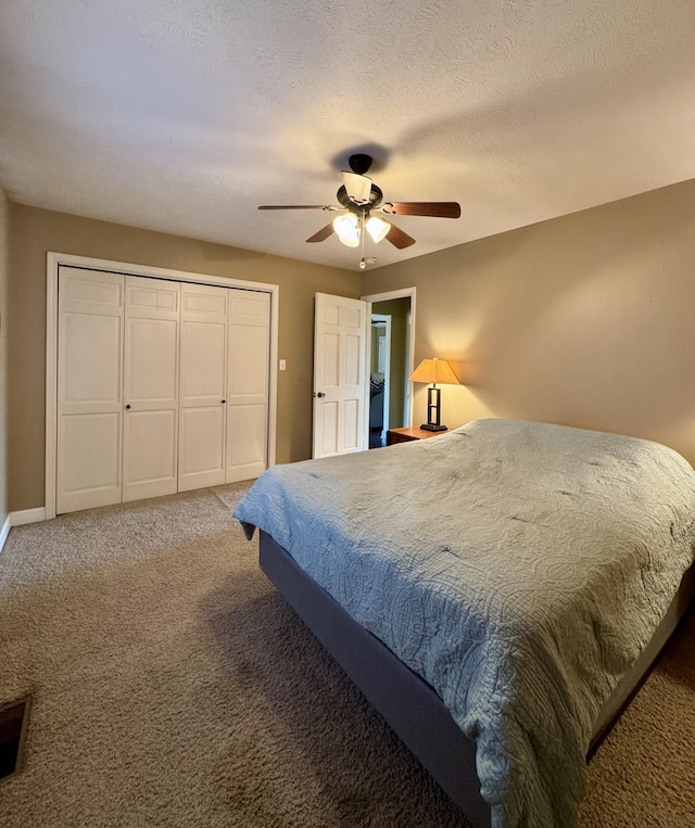 carpeted bedroom with a textured ceiling, ceiling fan, and a closet