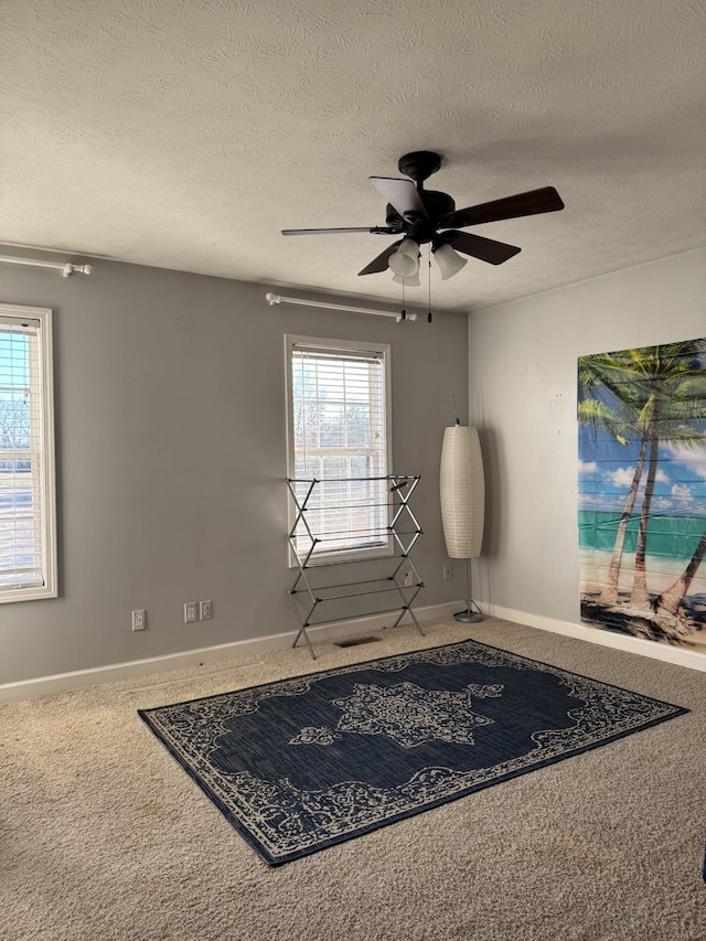 carpeted empty room featuring ceiling fan and a textured ceiling