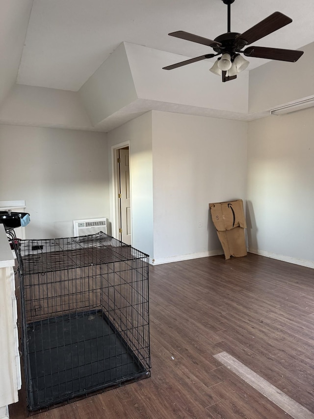 spare room with ceiling fan, dark wood-type flooring, a tray ceiling, and a wall mounted air conditioner