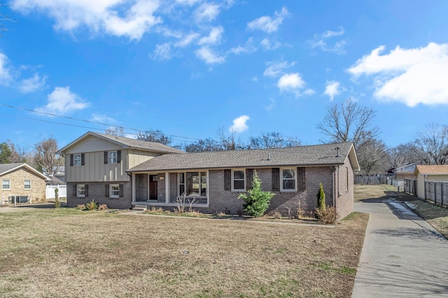 tri-level home with a front yard, covered porch, and cooling unit