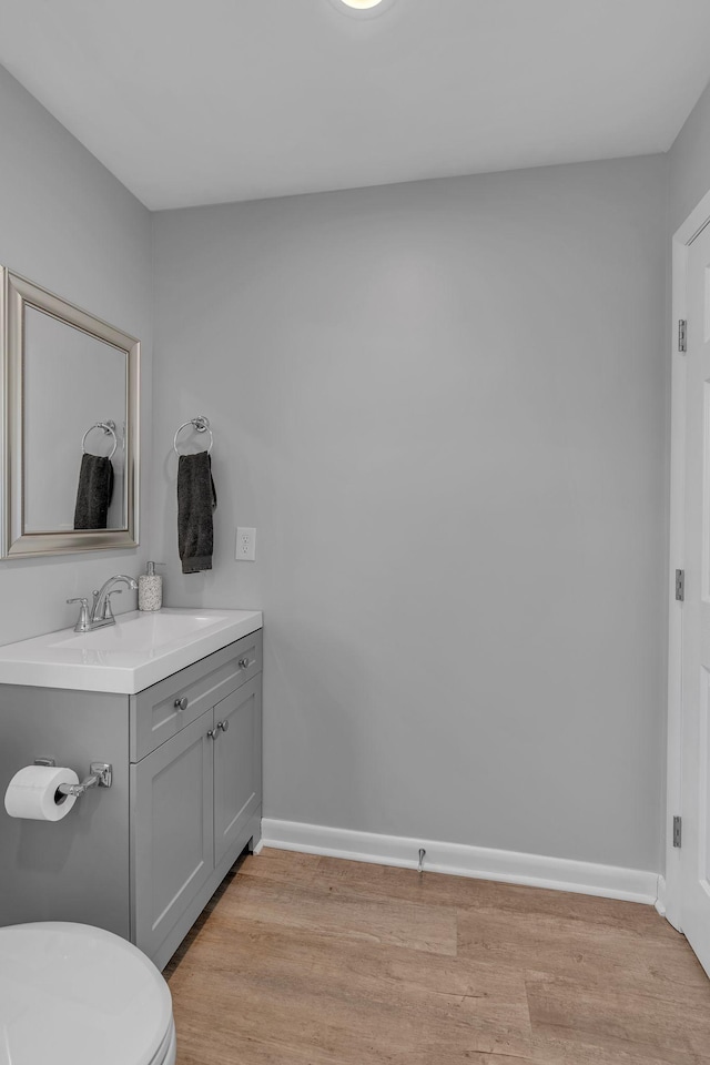 bathroom with toilet, wood-type flooring, and vanity