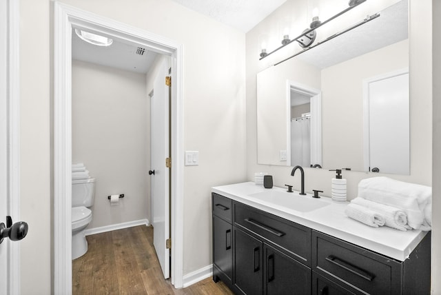 bathroom with toilet, a textured ceiling, hardwood / wood-style flooring, and vanity