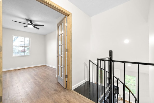 corridor featuring hardwood / wood-style floors, a textured ceiling, and french doors