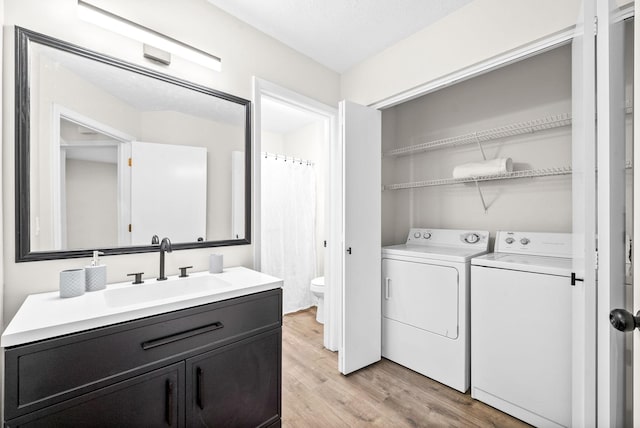 laundry room with sink, washer and clothes dryer, and light wood-type flooring