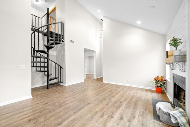 living room with high vaulted ceiling and light hardwood / wood-style flooring