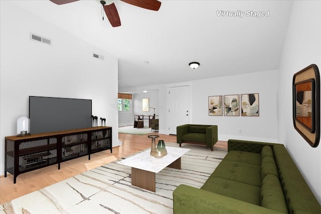 living room featuring ceiling fan, light hardwood / wood-style flooring, and vaulted ceiling