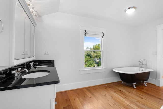 bathroom with wood-type flooring, a bath, vanity, and vaulted ceiling