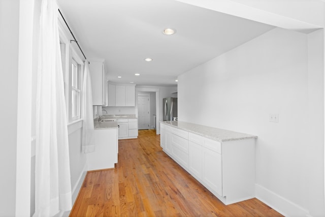 corridor featuring sink and light hardwood / wood-style flooring