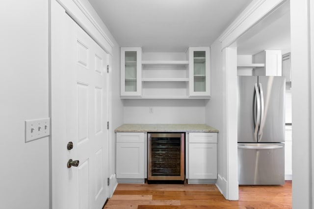 interior space featuring white cabinetry, light hardwood / wood-style floors, wine cooler, light stone countertops, and stainless steel refrigerator