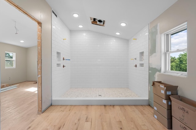 bathroom featuring lofted ceiling, wood-type flooring, and tiled shower