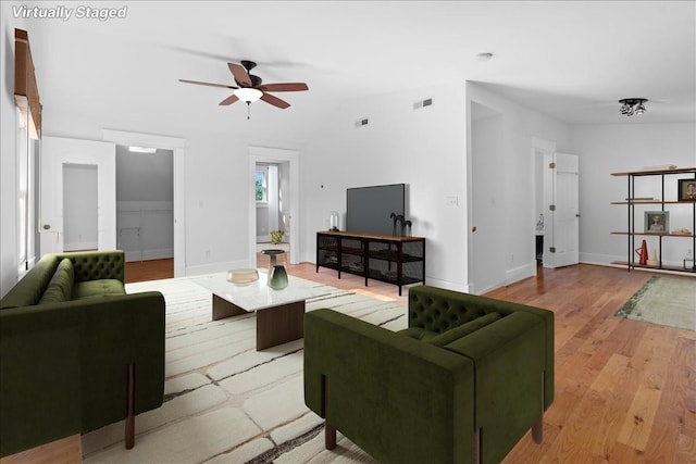 living room with ceiling fan, light wood-type flooring, and vaulted ceiling