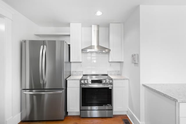 kitchen featuring decorative backsplash, white cabinets, appliances with stainless steel finishes, and wall chimney exhaust hood